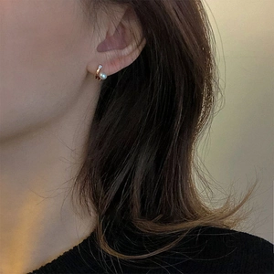 Close-up of elegant C-shaped double-layered pearl and zircon stud earrings on model