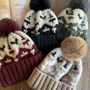 Detailed stack of winter knit hats with faux fur pom-poms and geometric patterns