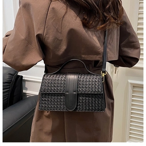 Close-up of black woven texture handbag with gold hardware and leather strap