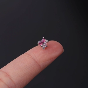Close-up of a tiny pink heart-shaped zircon stud earring held on a fingertip