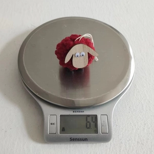 Detail showing red wool sheep Christmas ornament weighing 6.4g on a digital kitchen scale