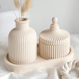 Detail view of cream-colored striped ceramic vase set with storage jar and oval tray