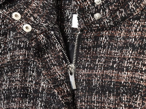 Detailed macro view of tweed jacket collar with silver zipper and snap button buckle