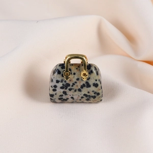 Macro detail of mini handbag pendant made from spotted beige stone with golden handle