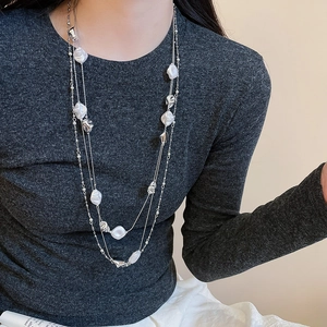 Detail of multi-layer silver long necklace with irregular beads and pearls on model