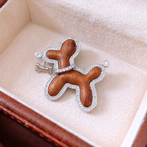 Detail of wooden balloon dog brooch with zircon inlay and small metal bone pendant