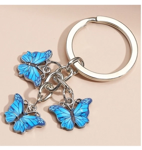 Macro view of a silver alloy keychain featuring three blue butterfly enamel pendants