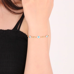 Close-up of a gold Evil Eye bracelet with blue enamel beads on a woman wrist