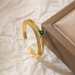 Detail shot of a gold ring with green triangle zircon and small diamonds on a jewelry box