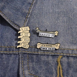 Funny skeletal enamel pins set with bone puns pinned on blue denim jacket lapel