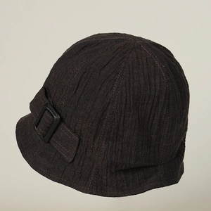 Detail of dark brown linen bucket hat showing textured pleats and black square buckle