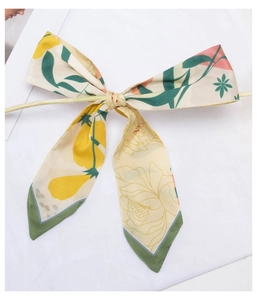 Detailed bow-tied floral scarf with yellow and green patterns on a wooden branch
