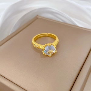 Close-up of gold plated ring with large zircon stone and crown setting on silk background