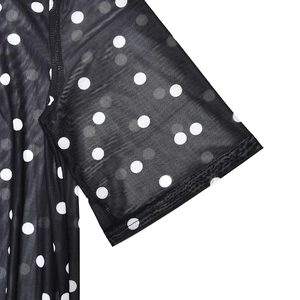 Close-up of sheer black mesh sleeve with white polka dots and stitched cuff detail