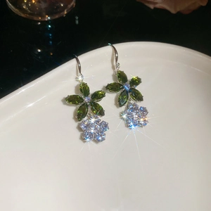 Vue macro de boucles d'oreilles doubles fleurs avec cristaux verts et transparents