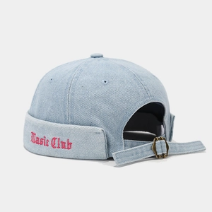 Détail de la boucle en métal et broderie Music Club rouge sur le bonnet en denim