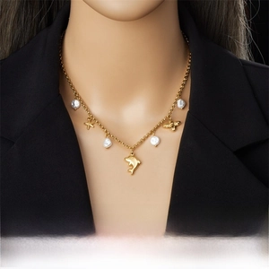 Detailed view of gold chain necklace featuring dolphin starfish and pearl charms