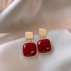 Close-up of red gemstone earrings with gold frames on luxury champagne silk fabric