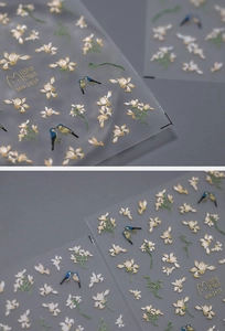 Detailed macro of 3D embossed nail stickers featuring floral and colorful bird patterns