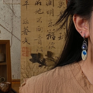 Detailed close-up of vintage flower earrings with blue enamel and crystal worn by a model
