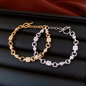 Close-up of gold and silver chain bracelets with zircon stones and OT buckle clasp