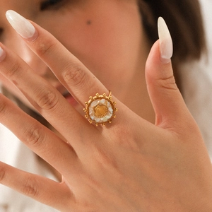 Gold stainless steel shell ring with a sunburst textured centerpiece on female model