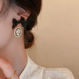 Close-up of a model wearing vintage black bow earrings with pearls and crystals