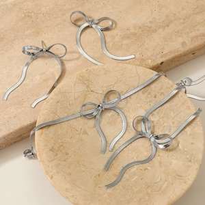 Elegant silver bow jewelry set with snake chain necklace and earrings on marble stands