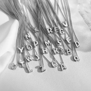 Macro shot of silver metal bubble letter pendants on a textured white background
