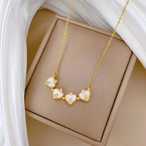 Détail du collier doré à quatre cœurs avec incrustations de nacre et petits cristaux