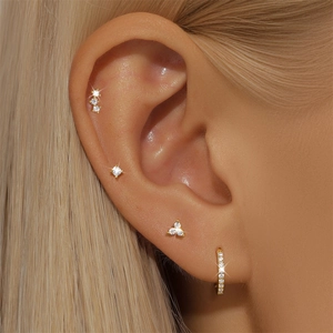 Detail of gold S925 sterling silver earring set with clear zircons on a female ear