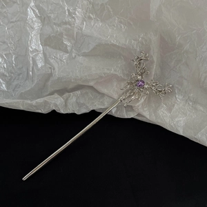 Detail of silver tassel hair stick with intricate floral pattern and a purple gemstone