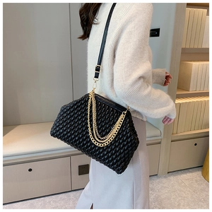Close-up of black quilted leather evening bag with golden chain and leather strap details