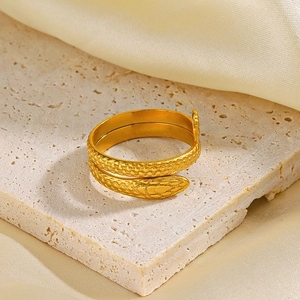 Retro vintage snake-shaped stainless steel gold plated open ring on stone and silk background