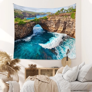 Détail d'une tapisserie bohème avec paysage marin suspendue sur un mur de chambre blanc
