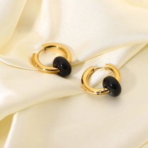 Detail of gold-plated hoop earrings with polished black oval beads on beige satin