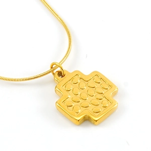 Gros plan sur pendentif croix dorée à motifs ovales sur une chaîne élégante en maille serpent