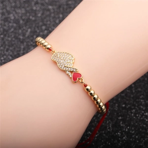 Adjustable red rope bracelet with golden heart hand gesture and sparkling zircons