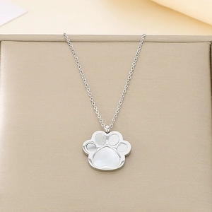 Detail of silver cat paw pendant with white shell inlay on a golden jewelry box