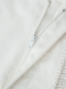 Vue macro d'une fermeture éclair blanche avec coutures et franges sur un pantalon femme