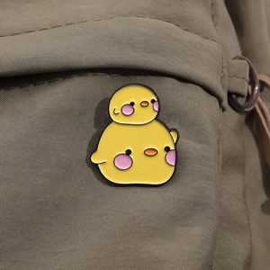 Nahaufnahme gelber Emaille-Anstecker in Entenform an einem grünen Rucksack
