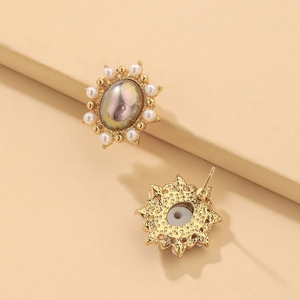 Detailed macro view of vintage oval pearl earrings with gold plating and Aurora stones