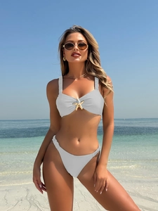 Detailed texture of white bikini set featuring gold starfish ornament and ruched straps