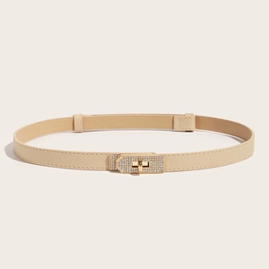 Detail of beige Saffiano leather skinny belt with elegant gold rhinestone twist buckle
