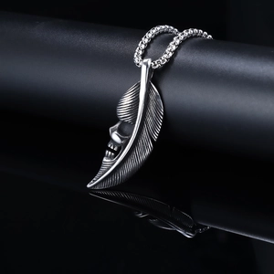 Macro shot of vintage silver skull feather pendant on bead chain with reflection
