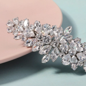 Macro d'une pince à cheveux argentée avec feuilles de zircon sur fond pastel