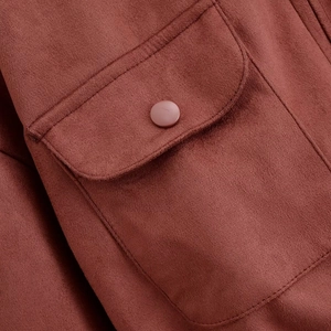 Detail of rust red suede jacket featuring a classic flap pocket and matching snap button
