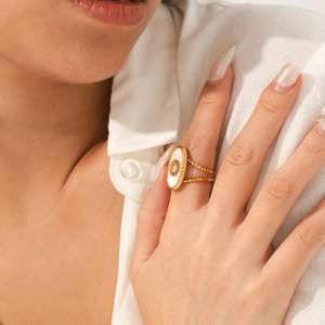 Detail of a vintage gold sun ring with white shell inlay worn by a female model
