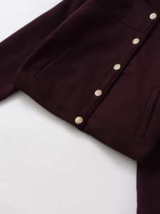 Nahaufnahme der burgunderroten Wolljacke mit Strukturstoff und goldenen Metallknöpfen