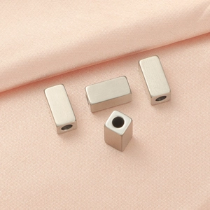 Square matte metal spacer beads for DIY jewelry making displayed on a soft pink fabric